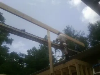 Carpenter setting a ridge beam over a new addition frame — Ice Dam Removal by Roofing Brothers in Garner