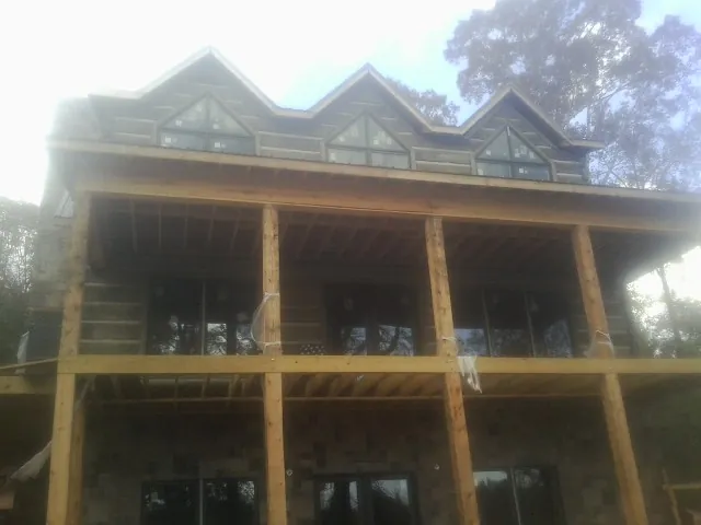 Dormers and porch framing on a large log home under construction — Roof Coating work by our crew in Garner