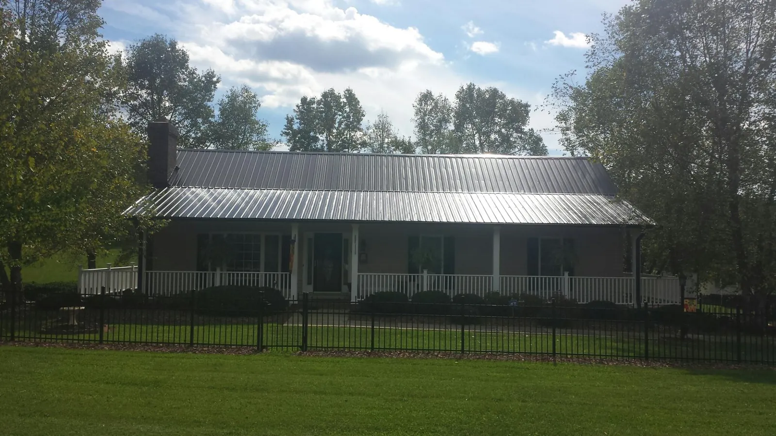 Gray metal roof on a brick ranch with a full width front porch — Gutter Guard Installation work by our crew in Garner
