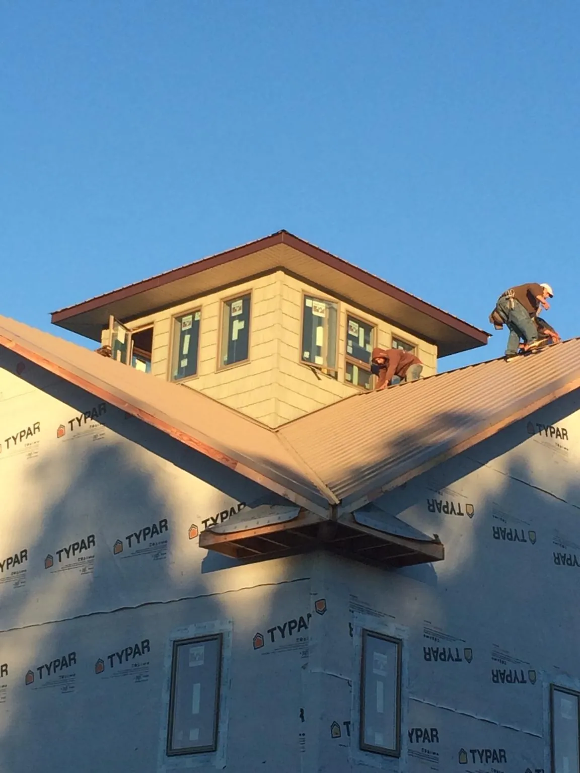 Roofers working around a rooftop cupola on a new metal roof at sunset — Roof Waterproofing in Garner by Roofing Brothers